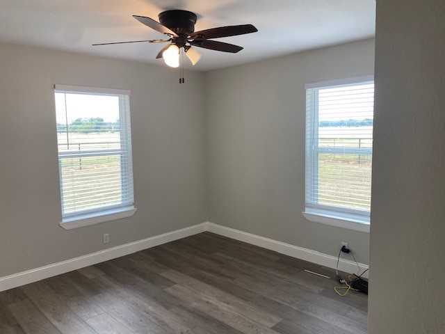 spare room with ceiling fan, plenty of natural light, and dark wood-type flooring