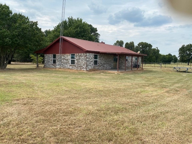 exterior space with stone siding, metal roof, a yard, and fence