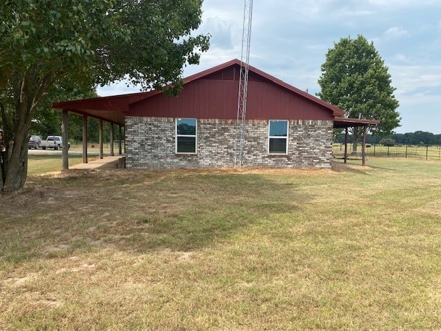 view of side of home with brick siding, a yard, and fence