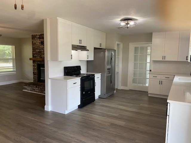 kitchen with white cabinetry, a fireplace, dark hardwood / wood-style flooring, brick wall, and black range with electric stovetop