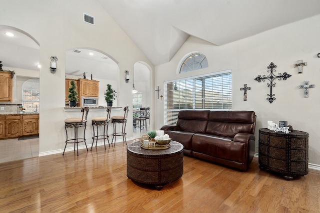 tiled living room featuring high vaulted ceiling and a wealth of natural light