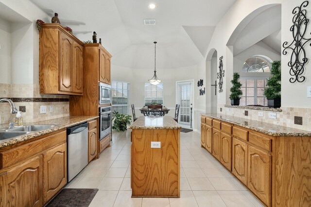 kitchen featuring light tile patterned flooring, a center island, stainless steel appliances, decorative backsplash, and plenty of natural light