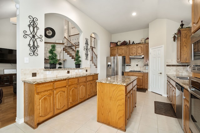 kitchen featuring sink, a center island, light hardwood / wood-style floors, appliances with stainless steel finishes, and backsplash