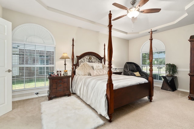 carpeted bedroom with ceiling fan and a tray ceiling