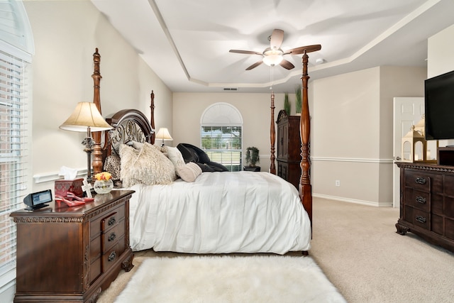 carpeted bedroom with ceiling fan and a tray ceiling