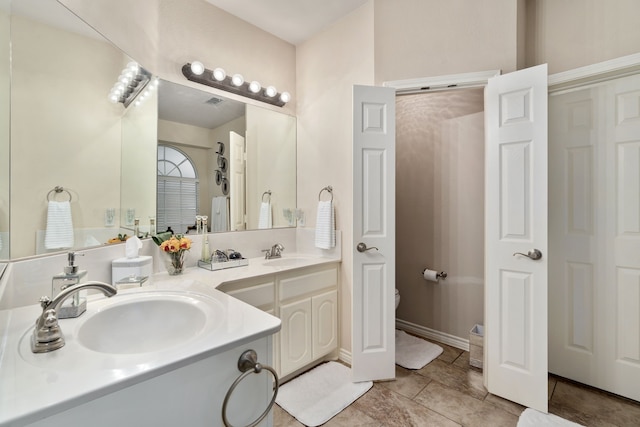 bathroom with tile patterned flooring, double sink vanity, and toilet