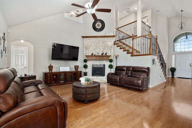 living room with light hardwood / wood-style flooring, a fireplace, ceiling fan, and high vaulted ceiling