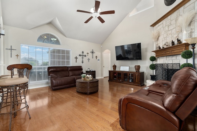 living room with a fireplace, wood-type flooring, high vaulted ceiling, and ceiling fan