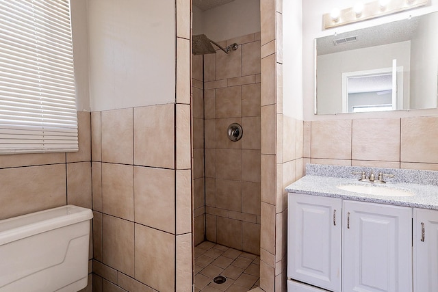 bathroom featuring tile walls, vanity, toilet, and tiled shower