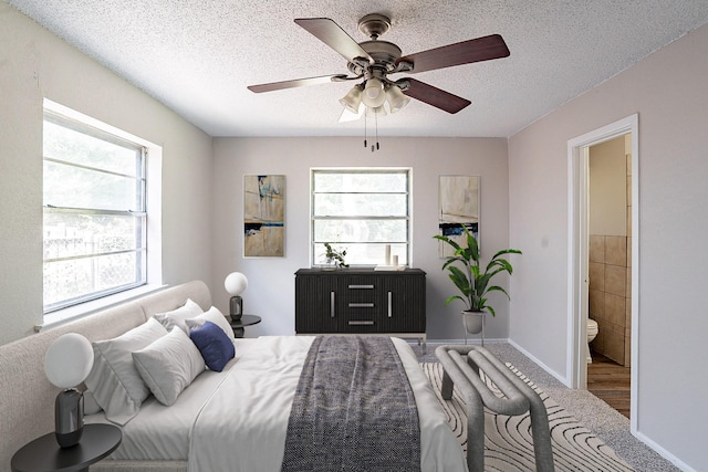 bedroom with ceiling fan, ensuite bath, and a textured ceiling