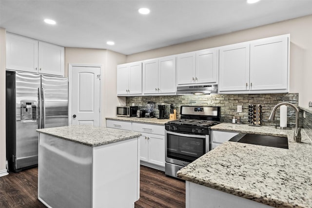 kitchen with a kitchen island, appliances with stainless steel finishes, sink, and light stone counters