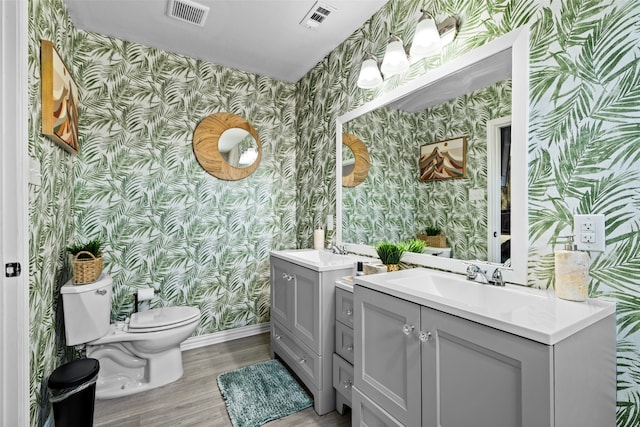 bathroom with hardwood / wood-style floors, toilet, and double sink vanity