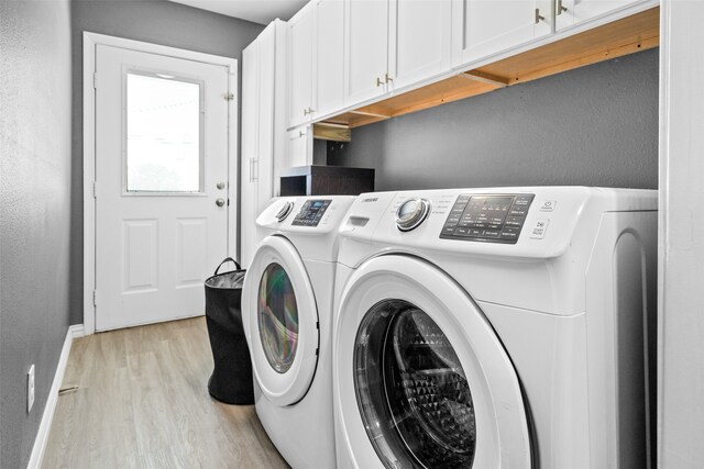 laundry room featuring washing machine and dryer, cabinets, and light hardwood / wood-style floors