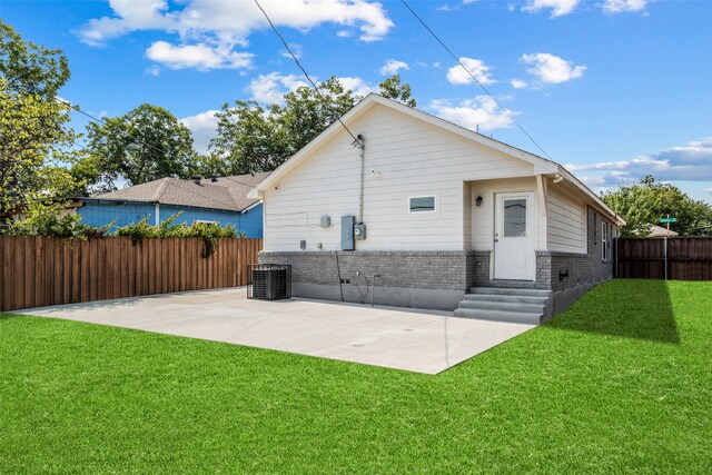 rear view of property with a patio area, cooling unit, and a yard