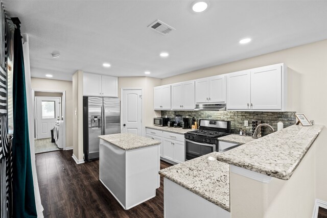 kitchen featuring separate washer and dryer, kitchen peninsula, a center island, dark hardwood / wood-style flooring, and stainless steel appliances