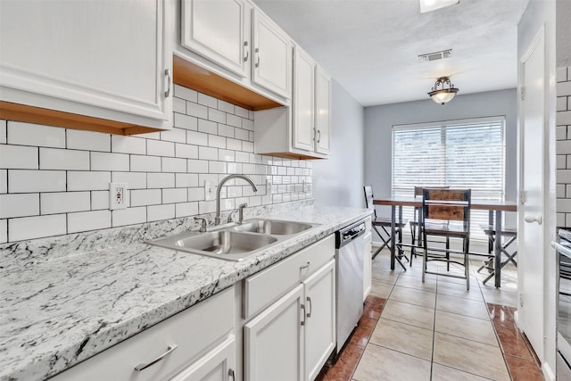 kitchen featuring light tile patterned flooring, sink, tasteful backsplash, stainless steel dishwasher, and white cabinets