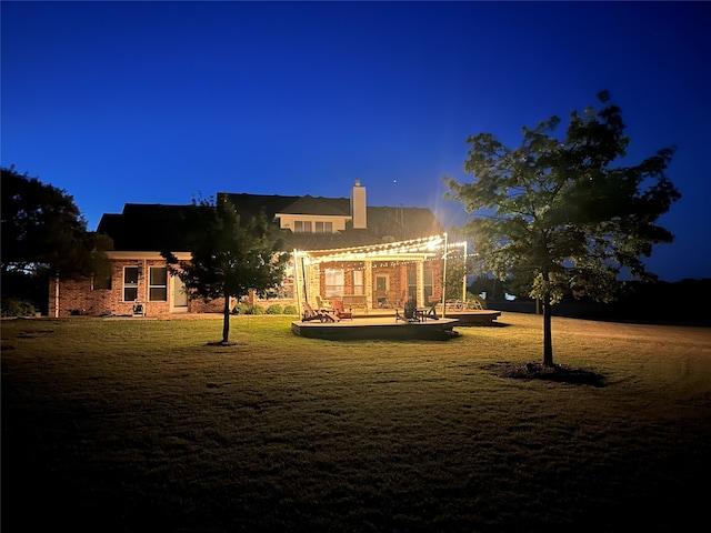 back house at night featuring a lawn