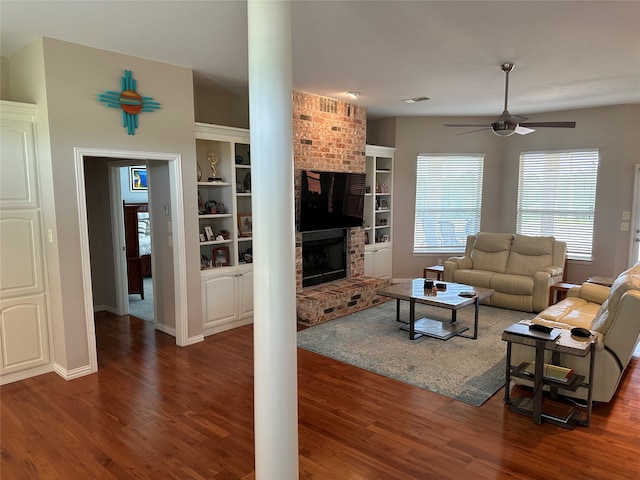 living room featuring ceiling fan, a brick fireplace, brick wall, built in features, and dark hardwood / wood-style flooring