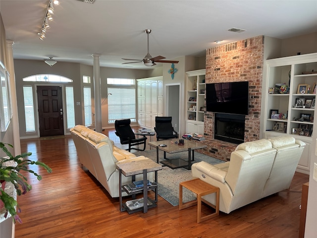 living room with a fireplace, ornate columns, track lighting, hardwood / wood-style flooring, and ceiling fan