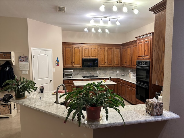 kitchen with light tile patterned floors, decorative backsplash, track lighting, black appliances, and light stone counters