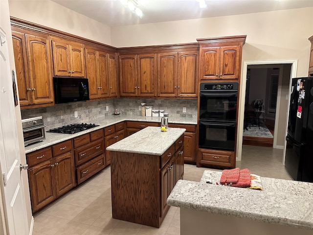 kitchen featuring backsplash, light tile patterned floors, and black appliances