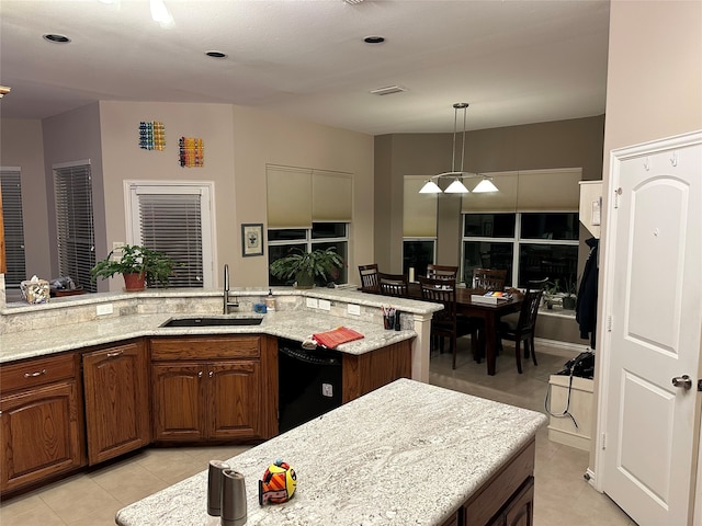 kitchen featuring black dishwasher, hanging light fixtures, light tile patterned flooring, an island with sink, and sink