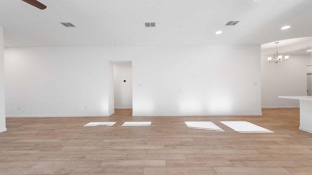 spare room featuring light hardwood / wood-style floors and a notable chandelier