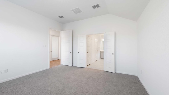 unfurnished bedroom with light colored carpet and vaulted ceiling