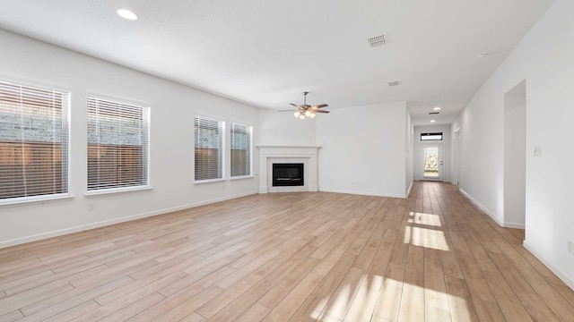 unfurnished living room featuring ceiling fan, plenty of natural light, and light hardwood / wood-style flooring