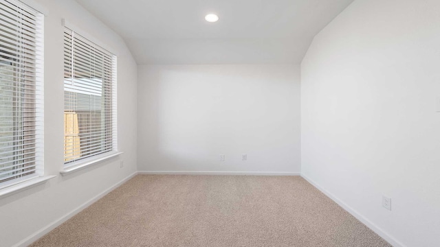 spare room featuring carpet floors and vaulted ceiling