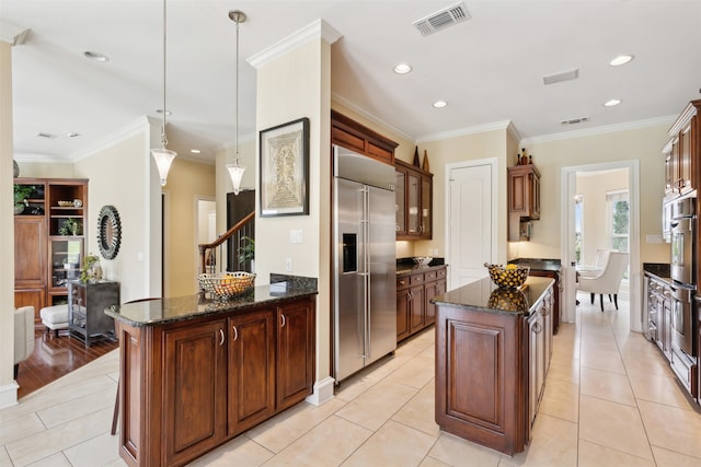 kitchen with appliances with stainless steel finishes, hanging light fixtures, light hardwood / wood-style floors, a kitchen island, and crown molding