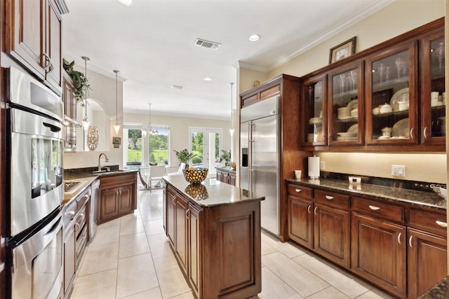 649 Oak Tree Cv, Cedar Hill, TX 75104 - kitchen featuring stainless steel appliances, a kitchen island, ornamental molding, dark stone countertops, and glass insert cabinets