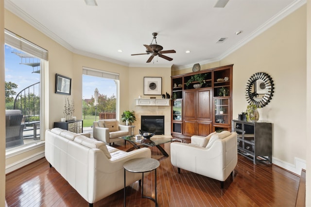 living room with a tiled fireplace, dark hardwood / wood-style floors, ceiling fan, and ornamental molding