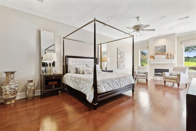 bedroom with a fireplace, wood-type flooring, ceiling fan, and crown molding