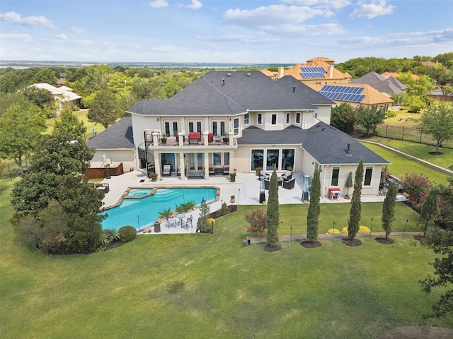 rear view of property featuring solar panels, a patio, a fenced in pool, and a lawn