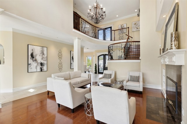 living room featuring a chandelier, dark wood-type flooring, ornate columns, and a towering ceiling