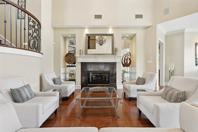 living room with dark hardwood / wood-style flooring, a tile fireplace, crown molding, and a towering ceiling