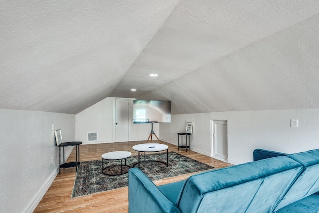 interior space featuring light wood-type flooring, lofted ceiling, and a textured ceiling