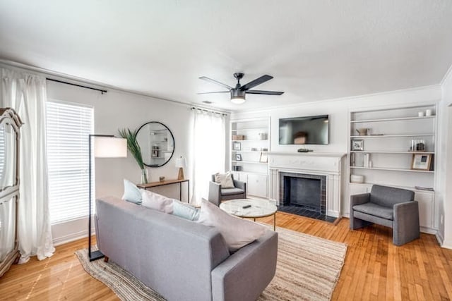 living room with built in features, light wood-type flooring, and ceiling fan