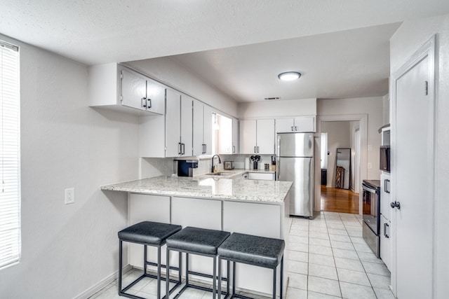 kitchen featuring light hardwood / wood-style flooring, range with electric cooktop, stainless steel fridge, kitchen peninsula, and white cabinetry