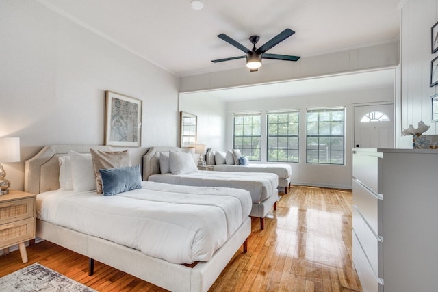 bedroom with light hardwood / wood-style floors, ornamental molding, and ceiling fan