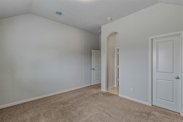 carpeted empty room with vaulted ceiling