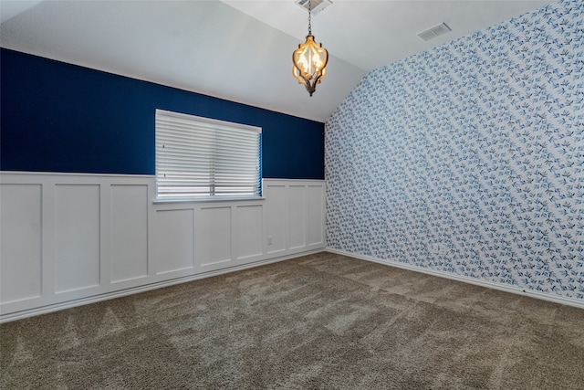 spare room featuring vaulted ceiling, carpet flooring, and a notable chandelier