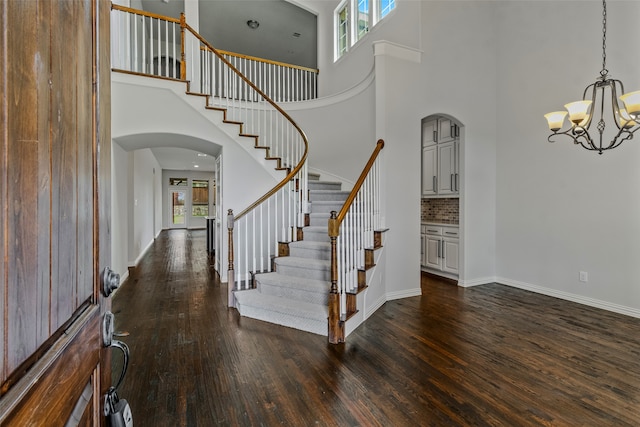 entrance foyer with a towering ceiling, dark hardwood / wood-style floors, and an inviting chandelier