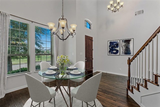 dining space with dark hardwood / wood-style floors, a notable chandelier, and a towering ceiling