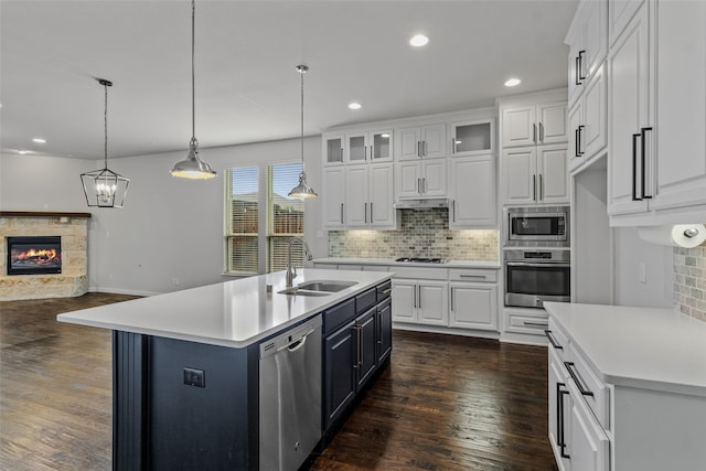 kitchen featuring a kitchen island with sink, sink, stainless steel appliances, and white cabinets