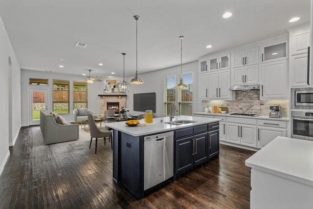 kitchen featuring appliances with stainless steel finishes, an island with sink, and white cabinets