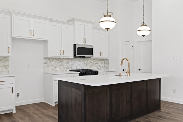 kitchen featuring white cabinetry, sink, decorative light fixtures, and range