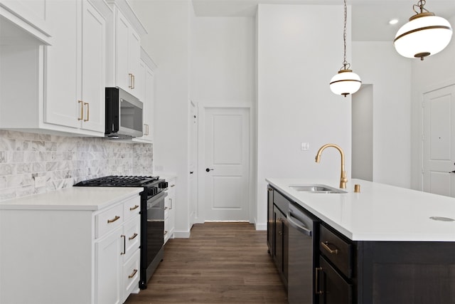 kitchen featuring pendant lighting, white cabinetry, sink, stainless steel appliances, and a center island with sink