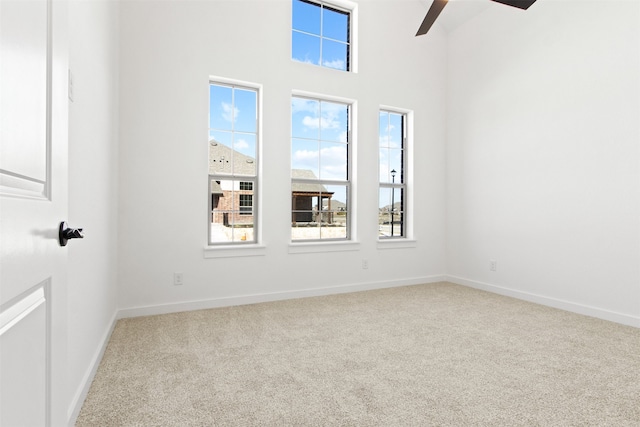 carpeted spare room featuring ceiling fan and a wealth of natural light